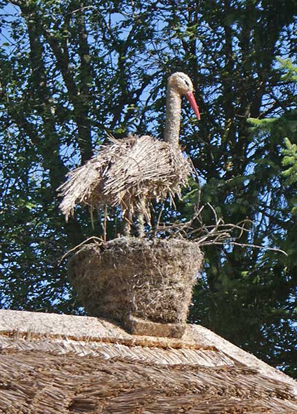 strohstorch.jpg - ... nistendem Stroh-Storch auf dem Dach.